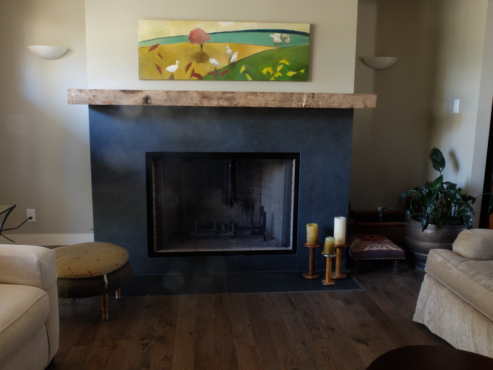 This is an example of a mid-sized eclectic family room in Edmonton with beige walls, dark hardwood floors, a standard fireplace, a wood fireplace surround and no tv.