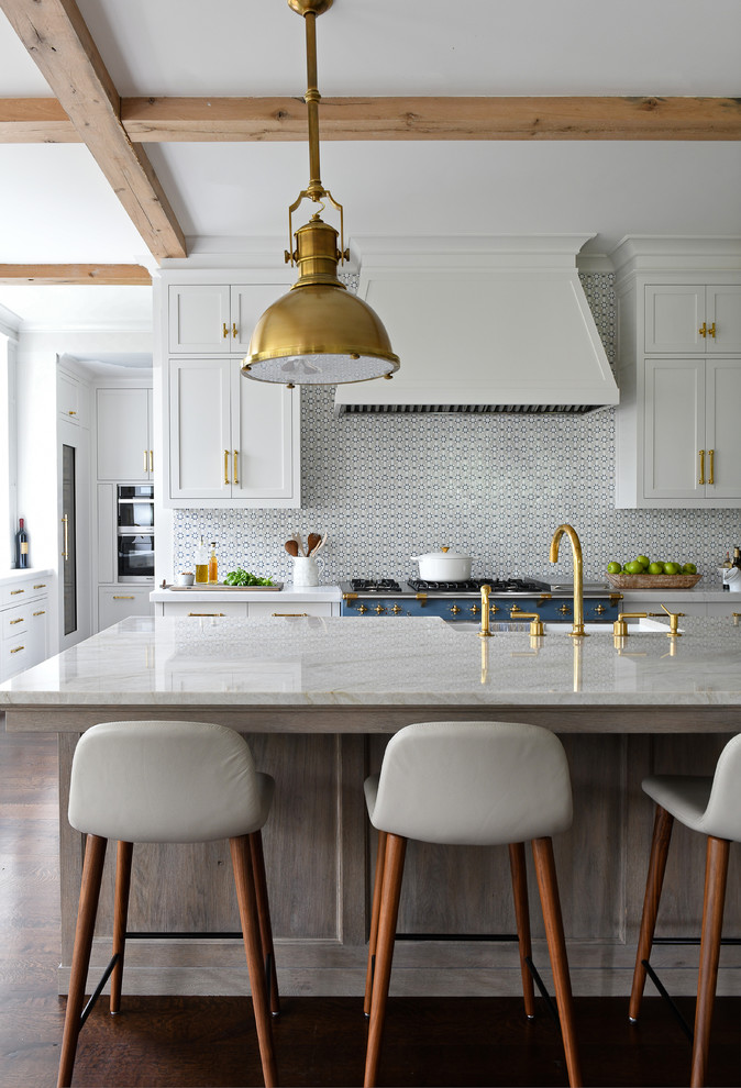 This is an example of a transitional kitchen in New York with a farmhouse sink, shaker cabinets, white cabinets, marble benchtops, multi-coloured splashback, coloured appliances, dark hardwood floors, with island, brown floor and white benchtop.