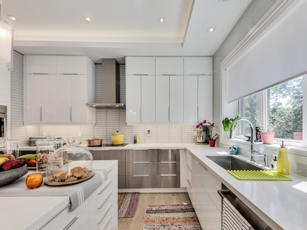 Inspiration for a contemporary l-shaped kitchen in Toronto with flat-panel cabinets, white cabinets, white splashback, stainless steel appliances, light hardwood floors and with island.