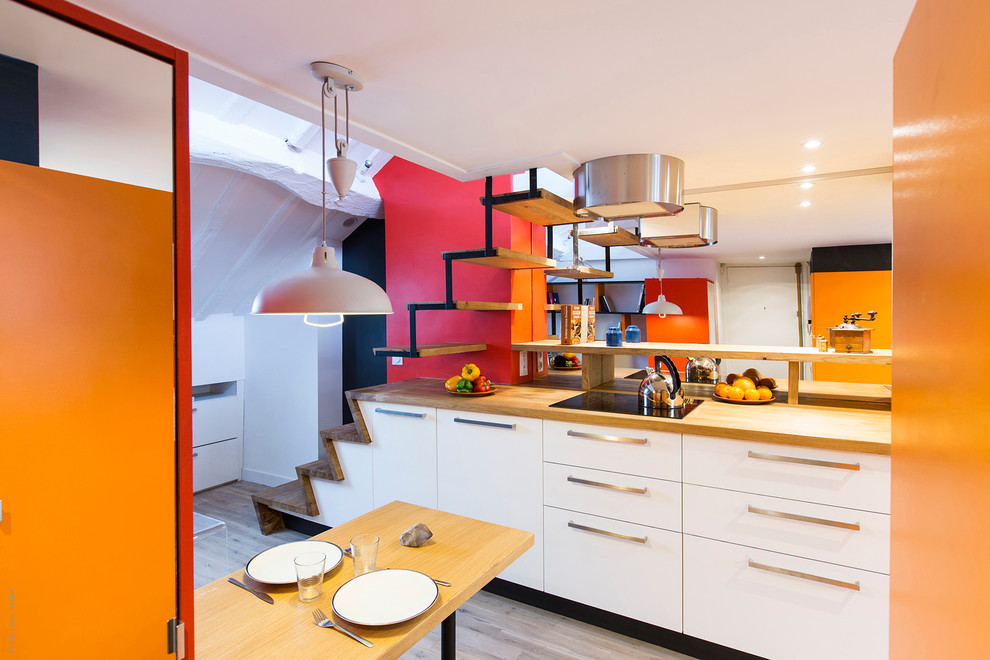 Mid-sized modern galley open plan kitchen in Paris with a single-bowl sink, beaded inset cabinets, stainless steel cabinets, wood benchtops, beige splashback, timber splashback, stainless steel appliances, dark hardwood floors, multiple islands and beige floor.