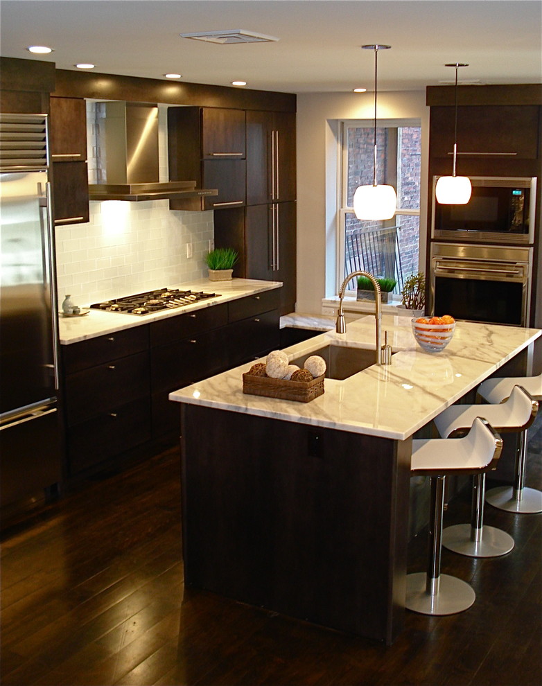 Photo of a contemporary galley kitchen in Boston with stainless steel appliances, marble benchtops, an undermount sink, flat-panel cabinets, dark wood cabinets, white splashback and subway tile splashback.