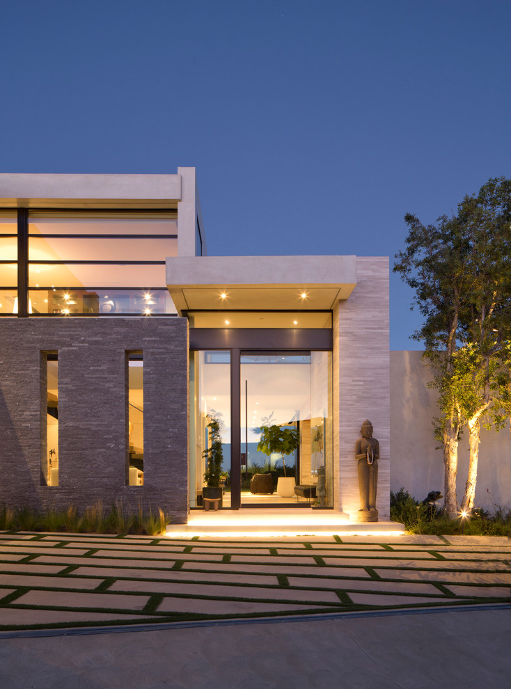 Photo of an expansive contemporary two-storey beige house exterior in Los Angeles with stone veneer and a flat roof.