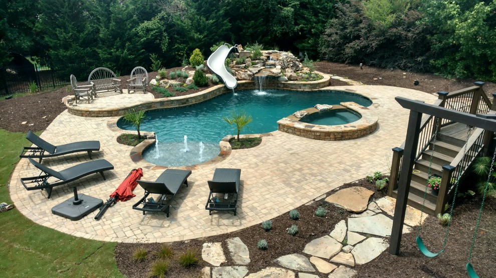 This is an example of a large backyard custom-shaped natural pool in Atlanta with a water slide and brick pavers.