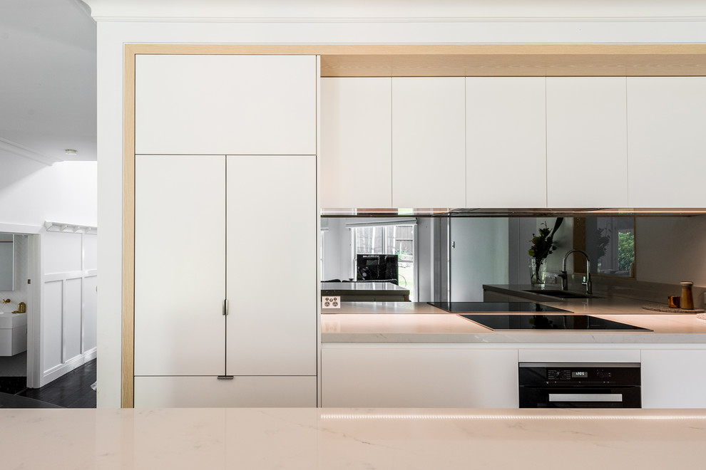 Design ideas for a large contemporary l-shaped open plan kitchen in Melbourne with an undermount sink, flat-panel cabinets, white cabinets, quartz benchtops, metallic splashback, mirror splashback, black appliances, dark hardwood floors, with island and brown floor.