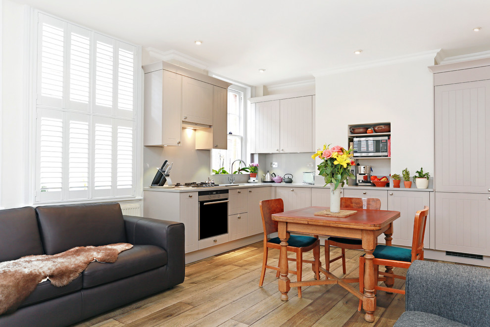 This is an example of a mid-sized transitional l-shaped eat-in kitchen in London with no island and light hardwood floors.
