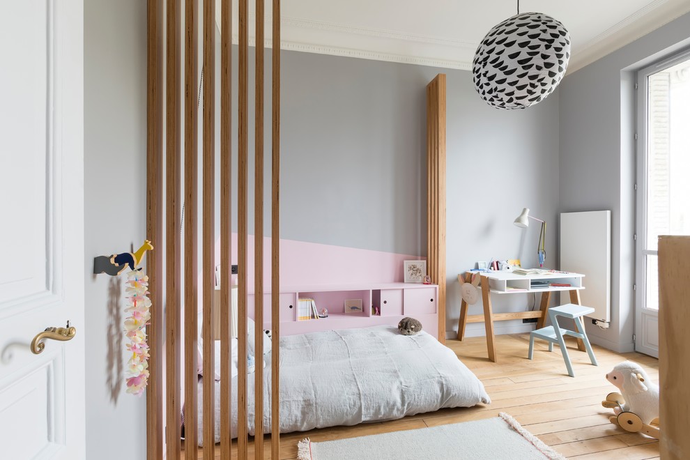 Large scandinavian kids' bedroom in Paris with grey walls, light hardwood floors and beige floor for girls and kids 4-10 years old.