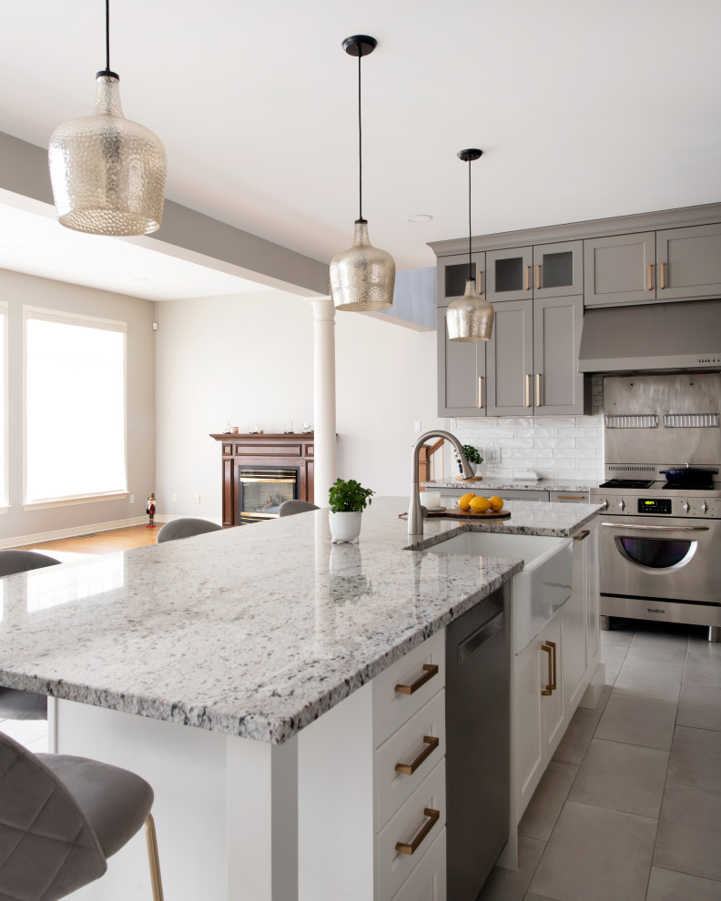 Open concept kitchen - mid-sized transitional l-shaped porcelain tile and gray floor open concept kitchen idea in Ottawa with a farmhouse sink, shaker cabinets, gray cabinets, granite countertops, white backsplash, ceramic backsplash, stainless steel appliances, an island and multicolored countertops