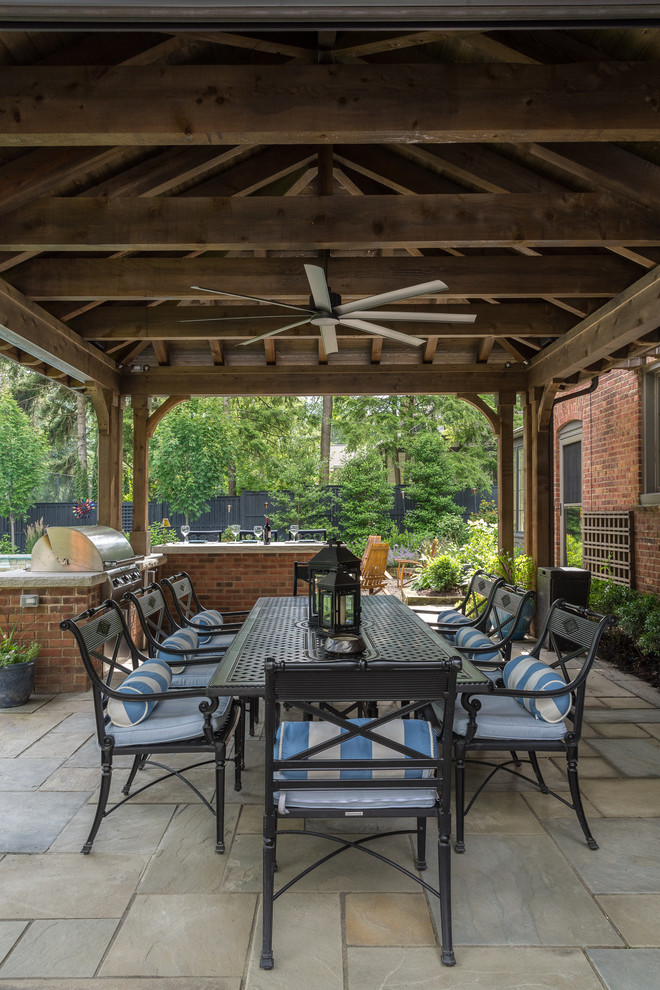 Design ideas for a large traditional backyard patio in Cleveland with an outdoor kitchen, natural stone pavers and a gazebo/cabana.