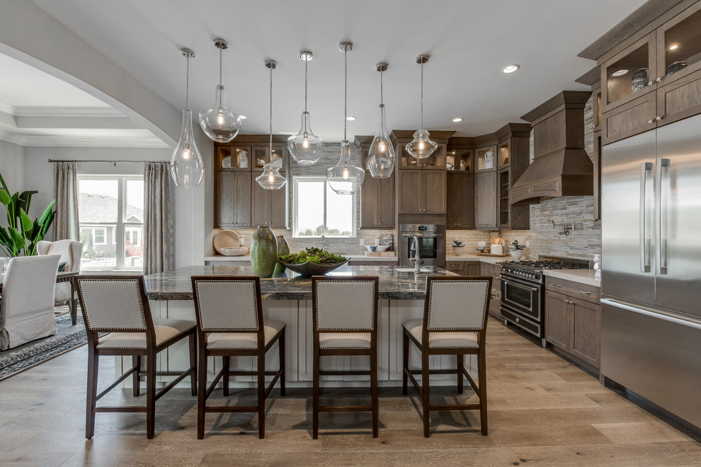 Photo of a large traditional l-shaped eat-in kitchen in Salt Lake City with an undermount sink, recessed-panel cabinets, dark wood cabinets, granite benchtops, grey splashback, stainless steel appliances, light hardwood floors, with island and brown floor.