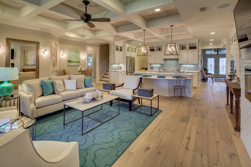 This is an example of a large beach style open concept family room in Miami with beige walls, light hardwood floors, a ribbon fireplace, a brick fireplace surround and a wall-mounted tv.
