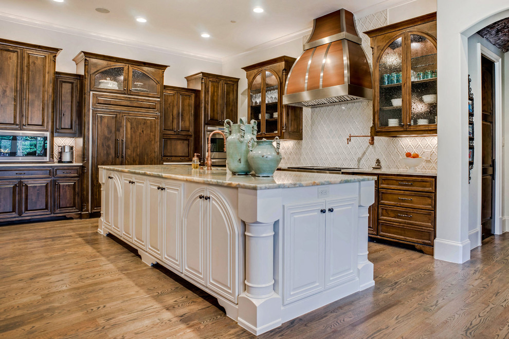 Inspiration for a large traditional u-shaped open plan kitchen in Dallas with a farmhouse sink, recessed-panel cabinets, dark wood cabinets, quartzite benchtops, blue splashback, ceramic splashback, panelled appliances, medium hardwood floors, multiple islands, brown floor and blue benchtop.