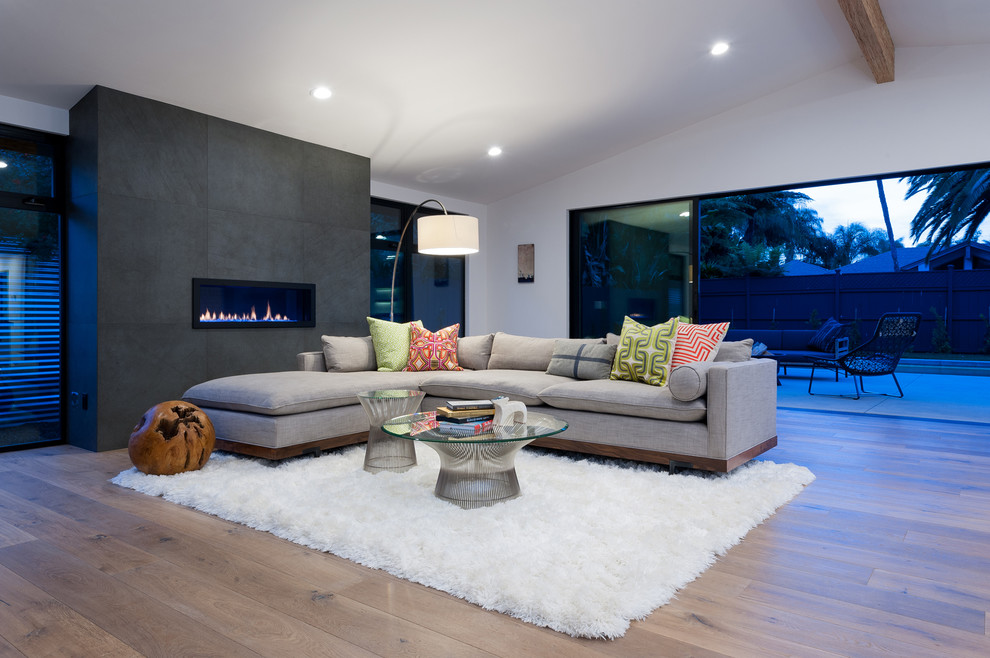 This is an example of a large contemporary open concept living room in San Diego with white walls, a ribbon fireplace, a concrete fireplace surround and light hardwood floors.
