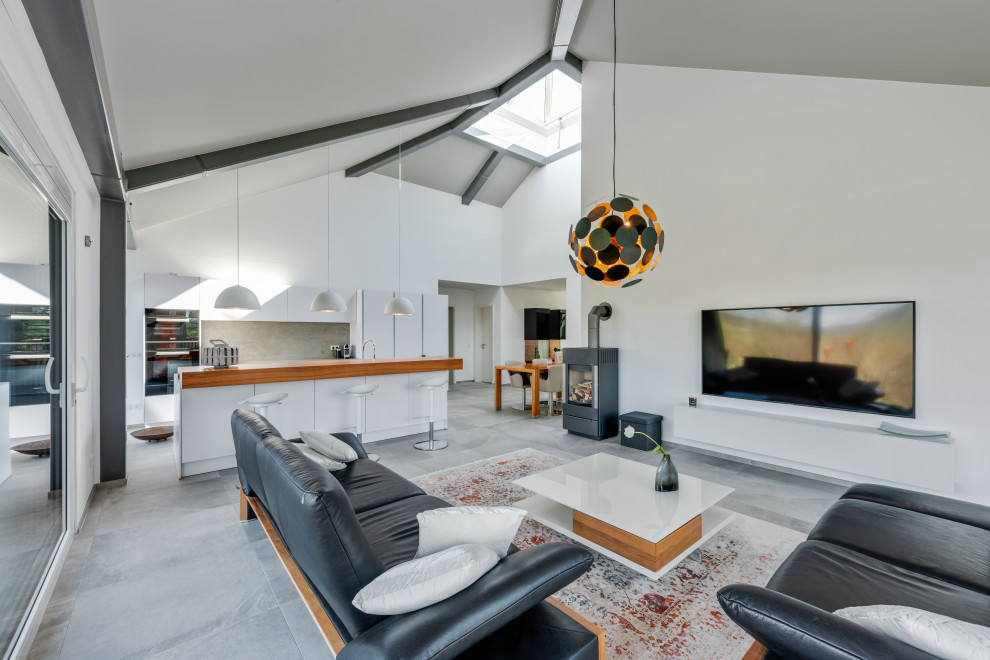 Wohnzimmer in grau-weiß With weißer Wandfarbe, Keramikboden, Kaminofen, Kaminumrandung aus Metall, TV-Wand, grauem Boden and freigelegten Dachbalken in Nuremberg