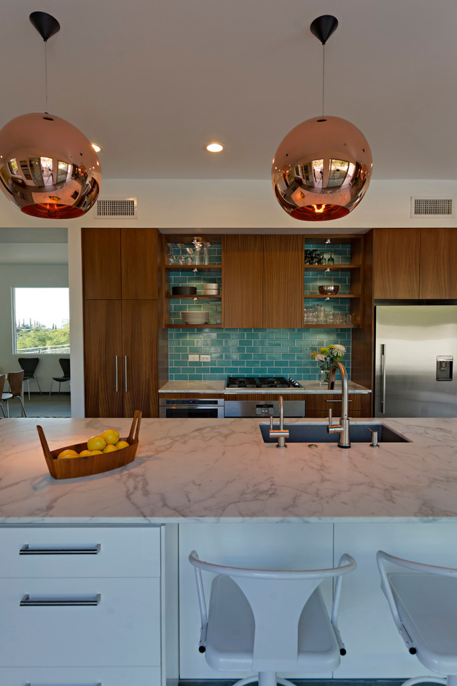 This is an example of a midcentury open plan kitchen in Phoenix with an undermount sink, flat-panel cabinets, medium wood cabinets, marble benchtops, blue splashback, ceramic splashback, stainless steel appliances, porcelain floors and with island.