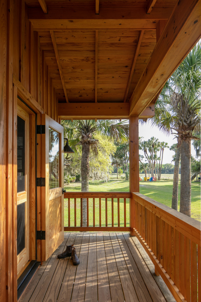 Inspiration pour un porche d'entrée de maison avant rustique de taille moyenne avec des colonnes, une terrasse en bois, une extension de toiture et un garde-corps en bois.
