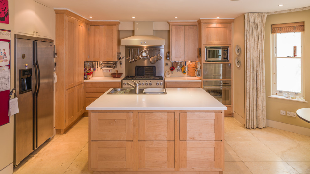 Contemporary galley open plan kitchen in Other with a drop-in sink, recessed-panel cabinets, light wood cabinets, solid surface benchtops, limestone floors, with island and beige floor.