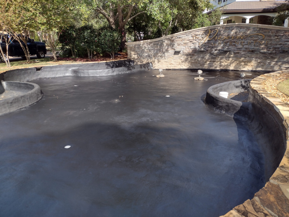 На фото: большой естественный бассейн произвольной формы на внутреннем дворе в морском стиле с покрытием из бетонных плит с