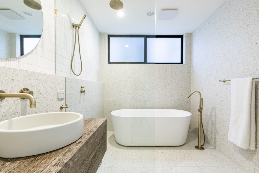 На фото: главная ванная комната в современном стиле с светлыми деревянными фасадами, отдельно стоящей ванной, душевой комнатой, унитазом-моноблоком, разноцветной плиткой, плиткой из травертина, полом из терраццо, разноцветным полом, открытым душем, тумбой под одну раковину и подвесной тумбой