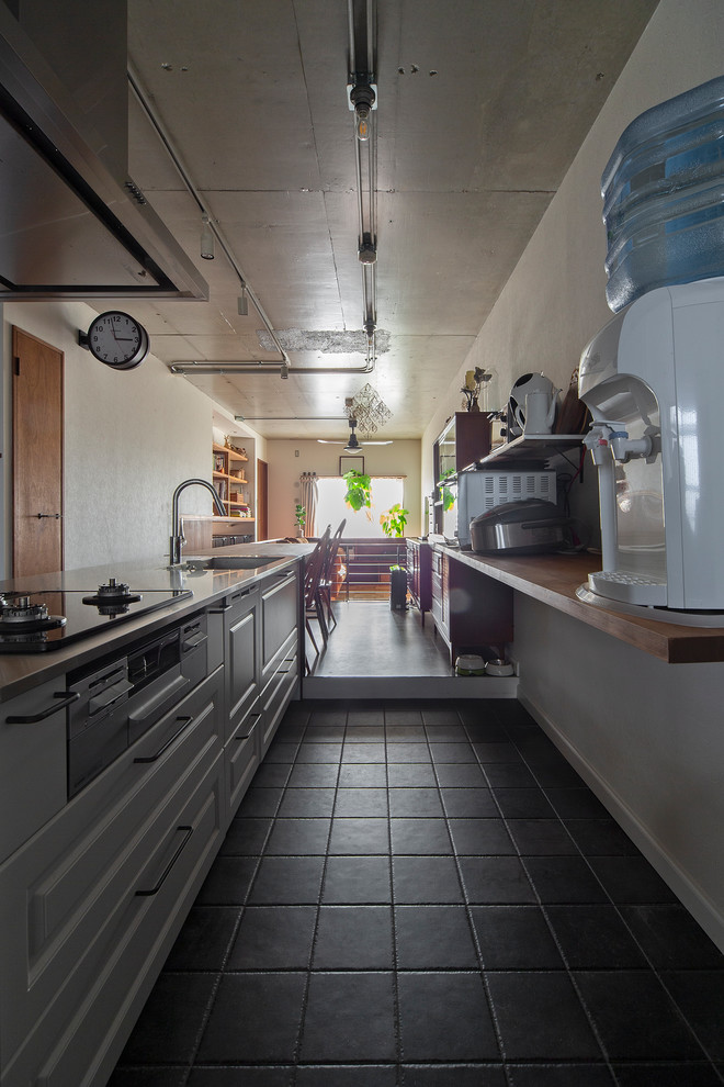 Photo of a small arts and crafts galley open plan kitchen in Osaka with an undermount sink, beaded inset cabinets, white cabinets, stainless steel benchtops, with island and grey floor.