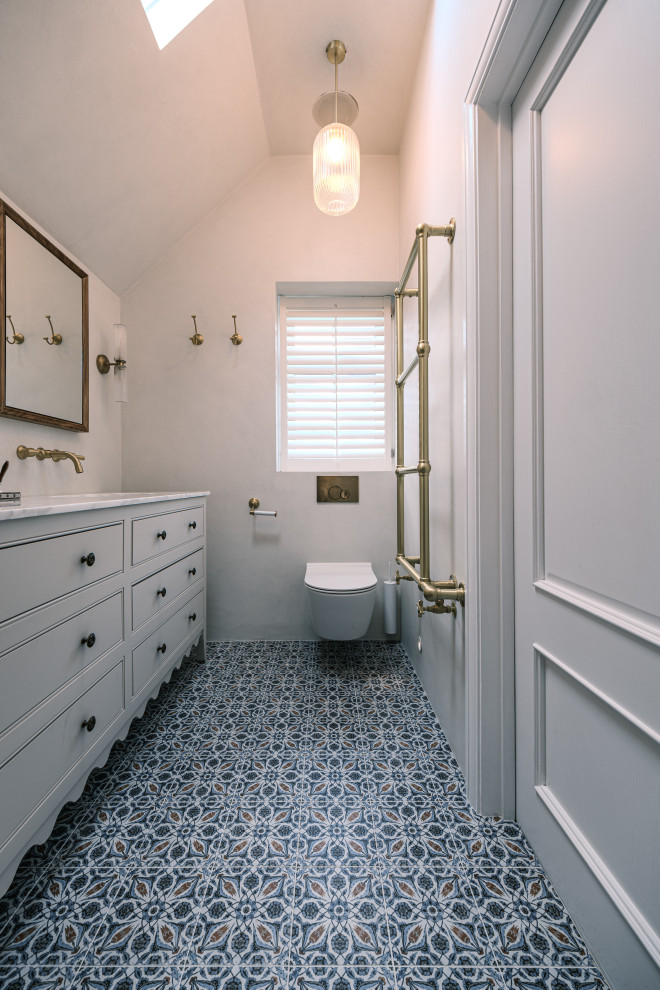 Immagine di un bagno di servizio classico di medie dimensioni con ante a filo, ante beige, WC sospeso, piastrelle beige, piastrelle di cemento, pareti beige, pavimento in gres porcellanato, lavabo da incasso, top in marmo, pavimento blu, top bianco, mobile bagno freestanding e soffitto a volta