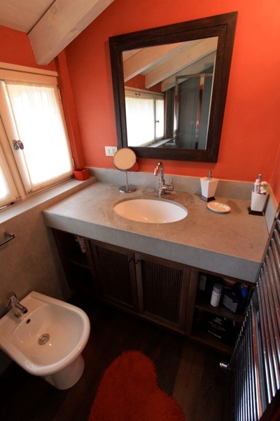 Idée de décoration pour une grande salle d'eau design avec un placard à porte affleurante, des portes de placard marrons, un carrelage rouge, un plan de toilette en béton, un plan de toilette gris, une douche à l'italienne, un bidet, un mur rouge, parquet foncé, un lavabo intégré, un sol marron et une cabine de douche avec un rideau.