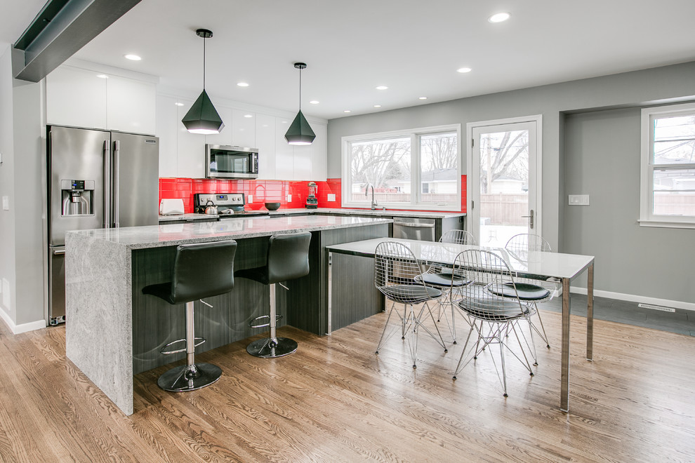 Design ideas for a contemporary l-shaped eat-in kitchen in Minneapolis with a drop-in sink, flat-panel cabinets, white cabinets, red splashback, subway tile splashback, stainless steel appliances, with island and grey benchtop.