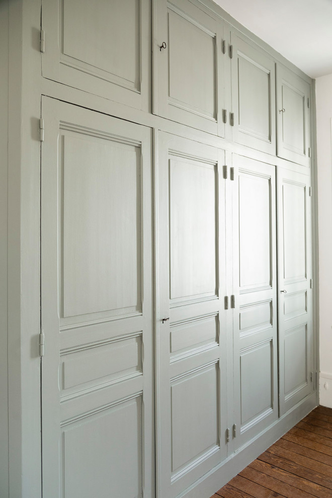 Idée de décoration pour un placard dressing tradition de taille moyenne et neutre avec un placard avec porte à panneau surélevé, des portes de placards vertess, un sol en bois brun et un sol marron.