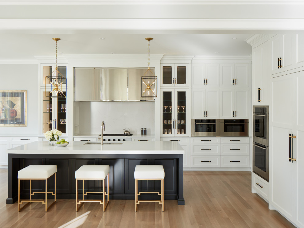 Example of a mid-sized transitional l-shaped light wood floor and gray floor eat-in kitchen design in Chicago with an undermount sink, white cabinets, quartz countertops, white backsplash, stone slab backsplash, stainless steel appliances, an island, white countertops and shaker cabinets