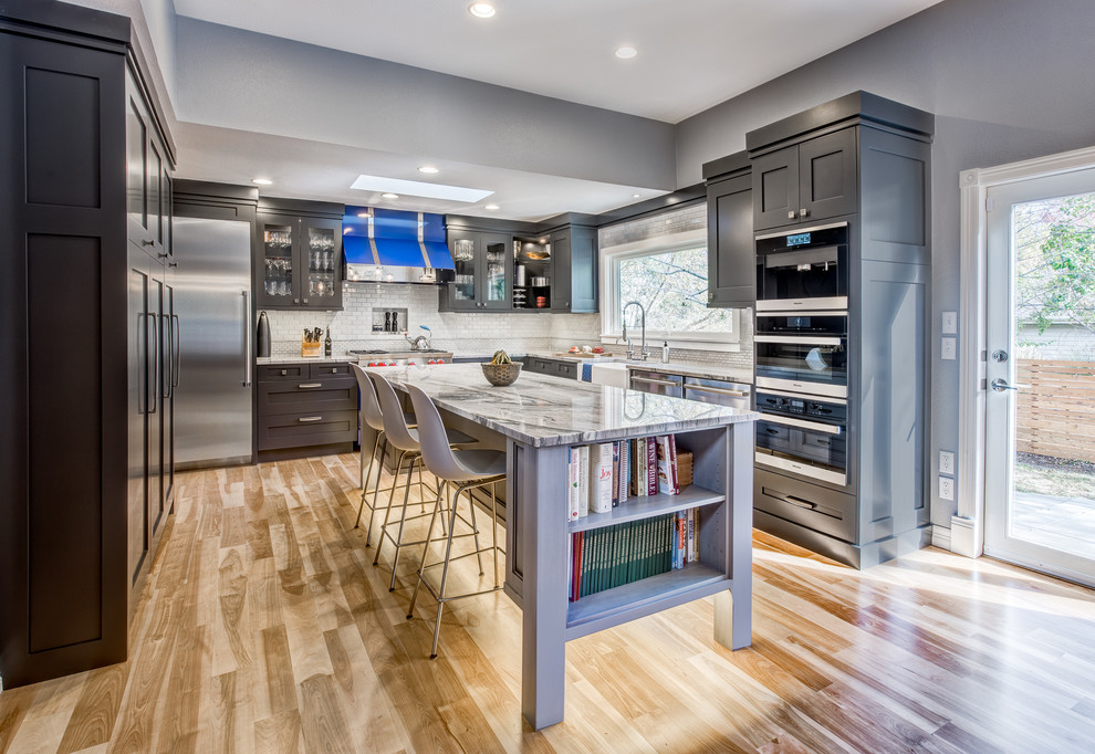 Eat-in kitchen - large transitional u-shaped light wood floor eat-in kitchen idea in Denver with a farmhouse sink, recessed-panel cabinets, gray cabinets, quartzite countertops, blue backsplash, ceramic backsplash, stainless steel appliances and an island