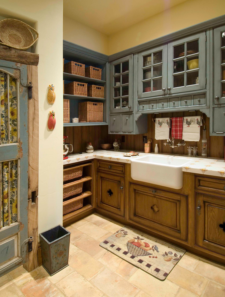 Country kitchen in Denver with a farmhouse sink, glass-front cabinets and blue cabinets.