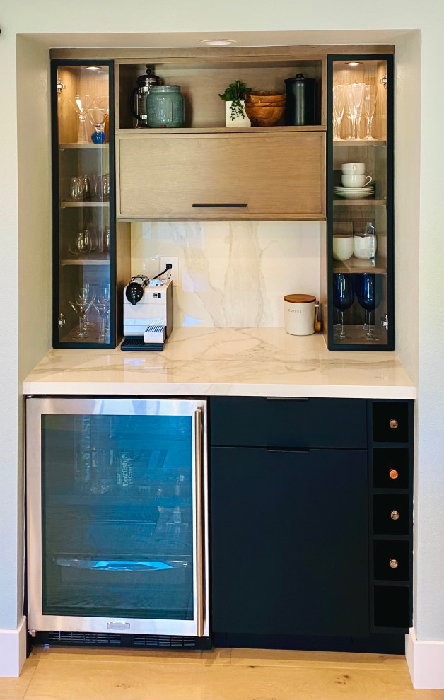 Immagine di una grande cucina contemporanea con ante lisce, ante nere, paraspruzzi bianco, elettrodomestici in acciaio inossidabile, parquet chiaro e top bianco