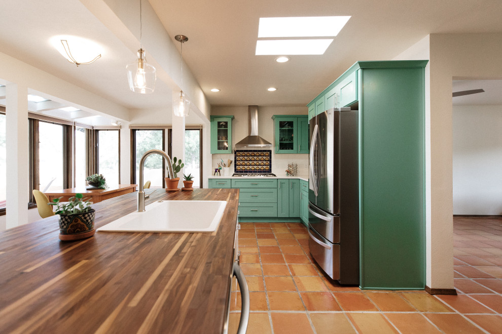 Inspiration for a mid-sized u-shaped eat-in kitchen in Albuquerque with a single-bowl sink, green cabinets, wood benchtops, multi-coloured splashback, subway tile splashback, stainless steel appliances, terra-cotta floors, with island, orange floor and multi-coloured benchtop.