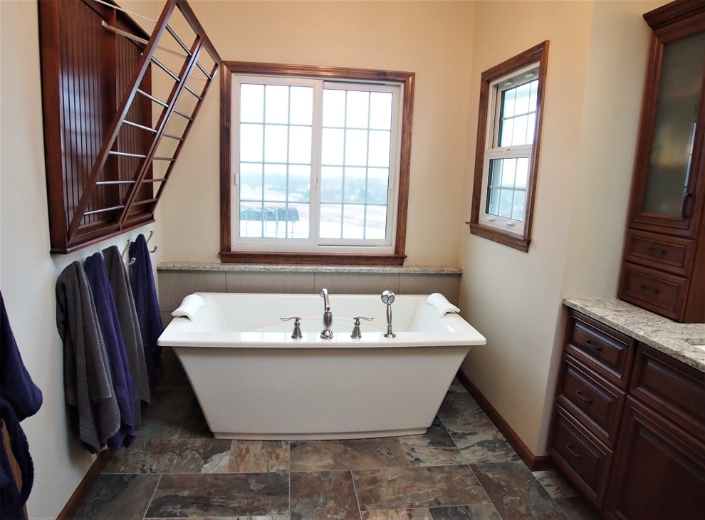 This is an example of a large traditional master bathroom in Bridgeport with raised-panel cabinets, medium wood cabinets, a freestanding tub, an alcove shower, a two-piece toilet, beige tile, porcelain tile, orange walls, porcelain floors, an undermount sink, quartzite benchtops, multi-coloured floor and a hinged shower door.
