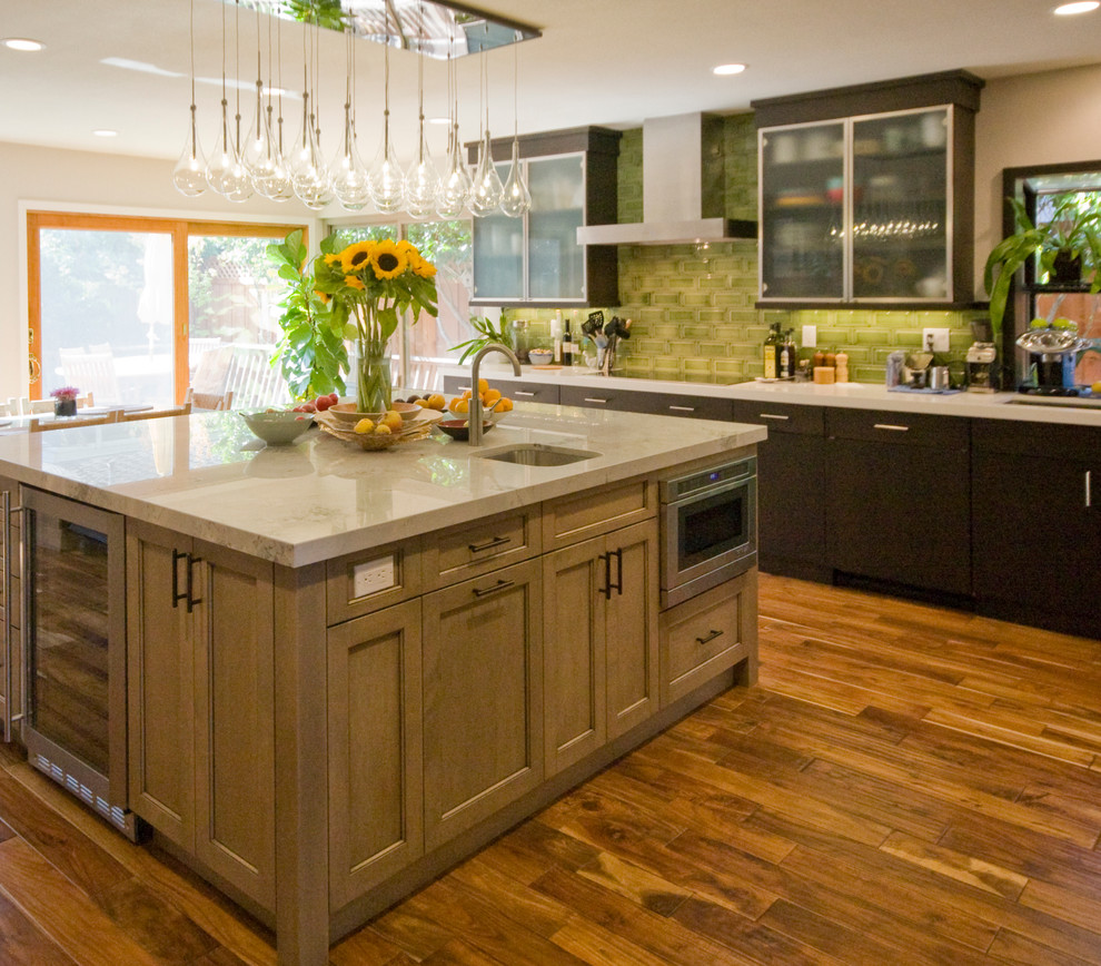Inspiration for a mid-sized transitional l-shaped medium tone wood floor eat-in kitchen remodel in San Francisco with an undermount sink, recessed-panel cabinets, medium tone wood cabinets, quartz countertops, green backsplash, subway tile backsplash, stainless steel appliances and an island