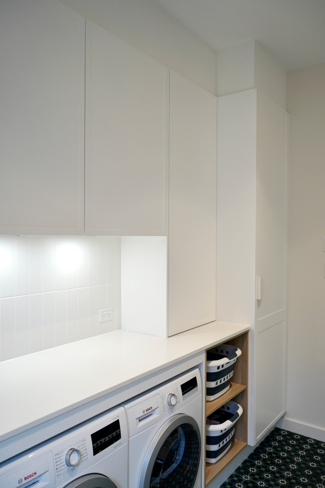 Photo of a mid-sized modern single-wall dedicated laundry room in Sydney with an undermount sink, shaker cabinets, white cabinets, quartz benchtops, white splashback, ceramic splashback, white walls, ceramic floors, a side-by-side washer and dryer, green floor and white benchtop.