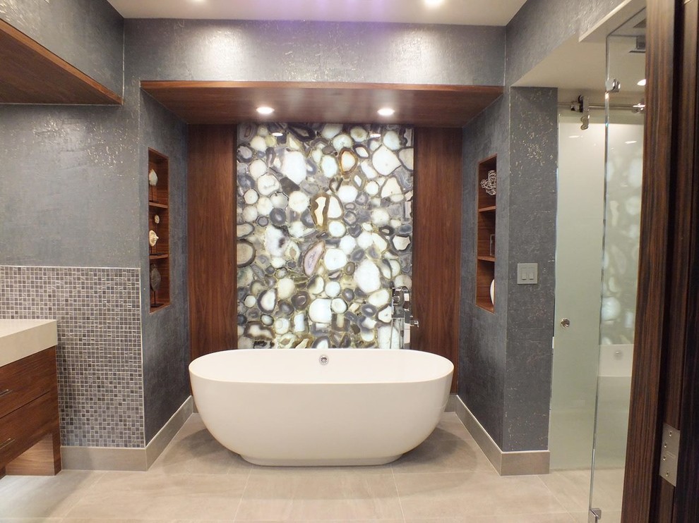 Photo of a mid-sized contemporary master bathroom in Miami with flat-panel cabinets, brown cabinets, a freestanding tub, an alcove shower, a bidet, multi-coloured tile, stone tile, grey walls, porcelain floors, an undermount sink, engineered quartz benchtops, beige floor and a hinged shower door.