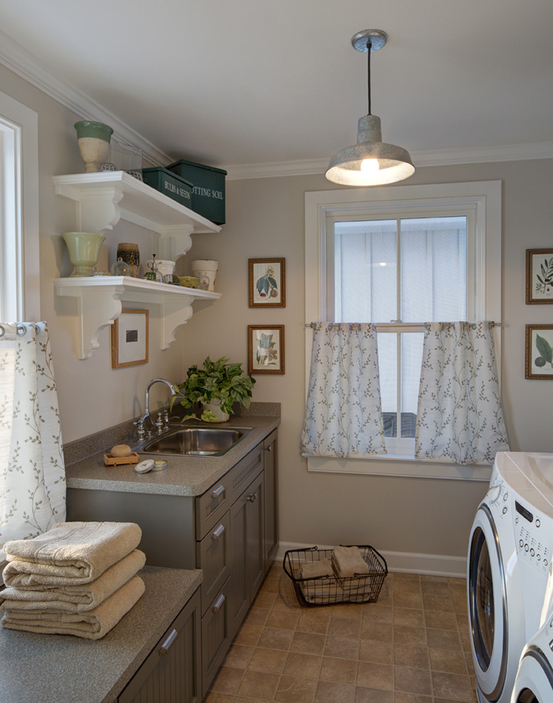 Inspiration for a mid-sized country galley utility room in Milwaukee with a drop-in sink, grey cabinets, laminate benchtops, beige walls, laminate floors and a side-by-side washer and dryer.