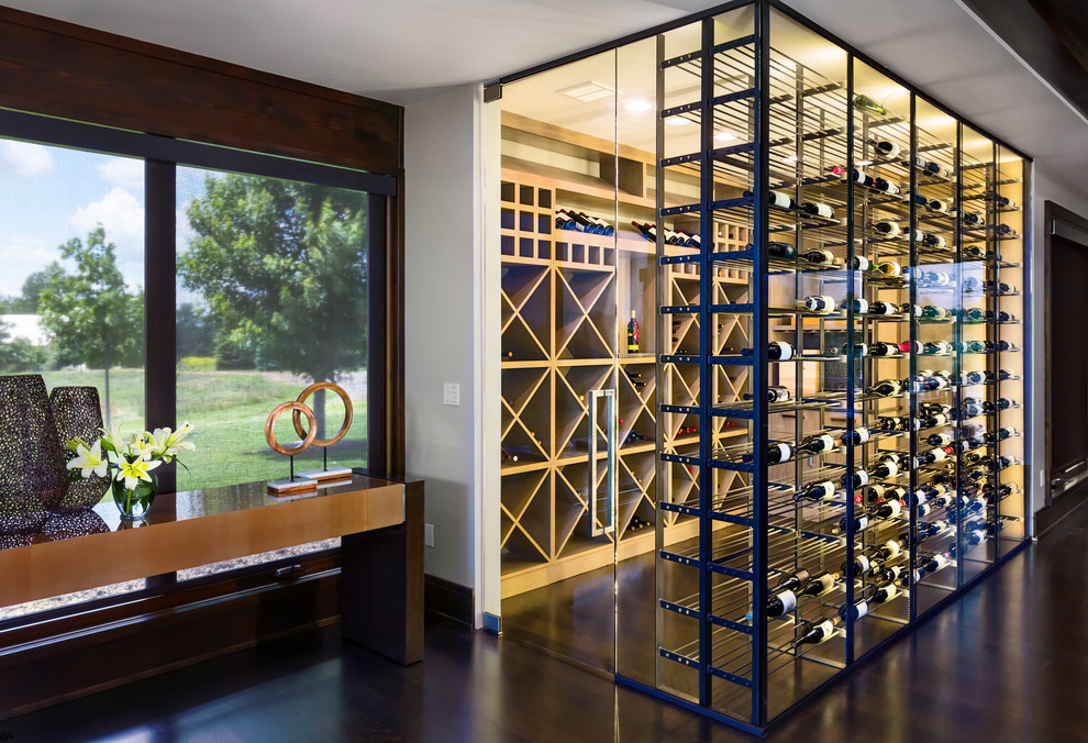Photo of a large contemporary wine cellar in Omaha with dark hardwood floors, storage racks and brown floor.