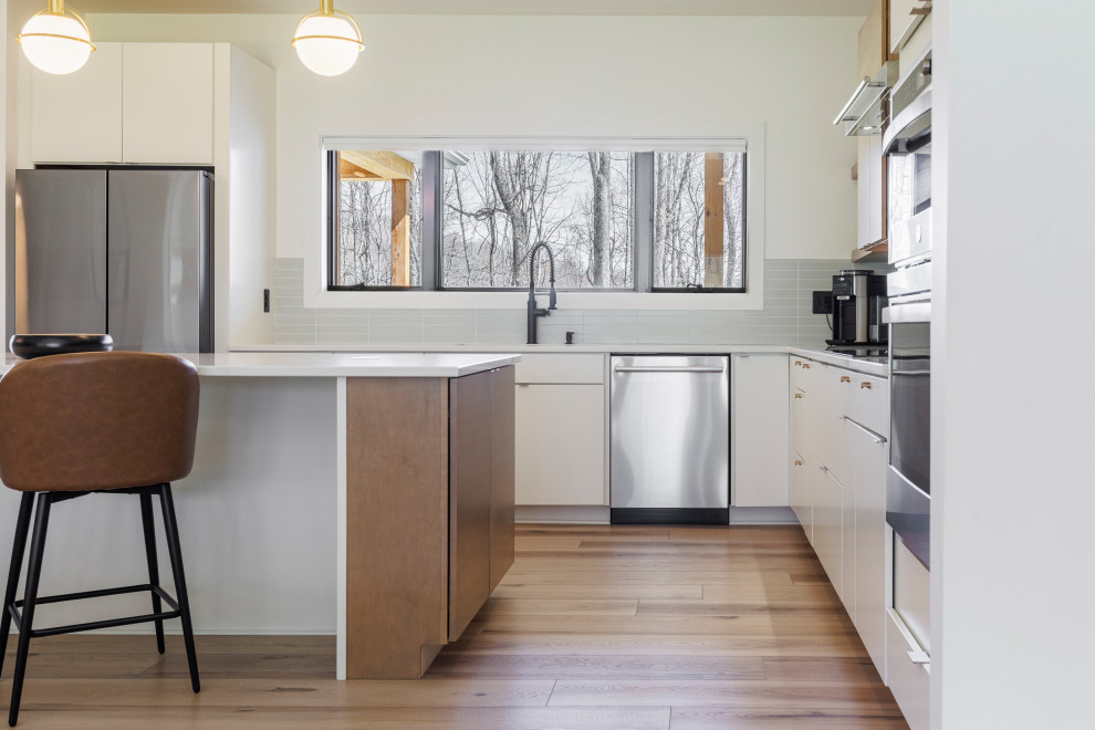 Inspiration for a mid-sized scandinavian l-shaped open plan kitchen in Charleston with a drop-in sink, flat-panel cabinets, white cabinets, limestone benchtops, grey splashback, ceramic splashback, stainless steel appliances, vinyl floors, with island, beige floor, white benchtop and vaulted.