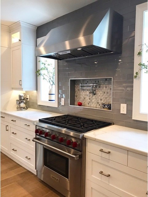 Large transitional single-wall light wood floor open concept kitchen photo in Philadelphia with an undermount sink, shaker cabinets, white cabinets, marble countertops, gray backsplash, terra-cotta backsplash, stainless steel appliances and an island
