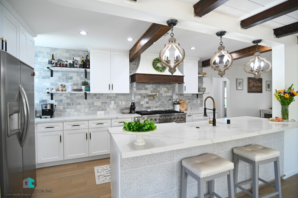 This is an example of a contemporary kitchen in Los Angeles with a belfast sink, white cabinets, quartz worktops, grey splashback, stainless steel appliances, vinyl flooring, an island, brown floors and exposed beams.