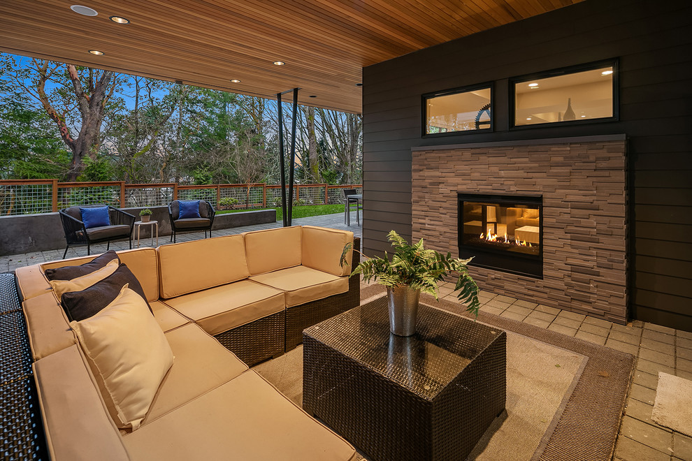 Design ideas for a contemporary patio in Seattle with with fireplace, concrete pavers and a roof extension.