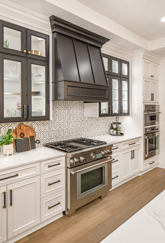 Example of a huge transitional l-shaped light wood floor and exposed beam eat-in kitchen design in Omaha with a farmhouse sink, recessed-panel cabinets, black cabinets, quartz countertops, paneled appliances, an island and white countertops