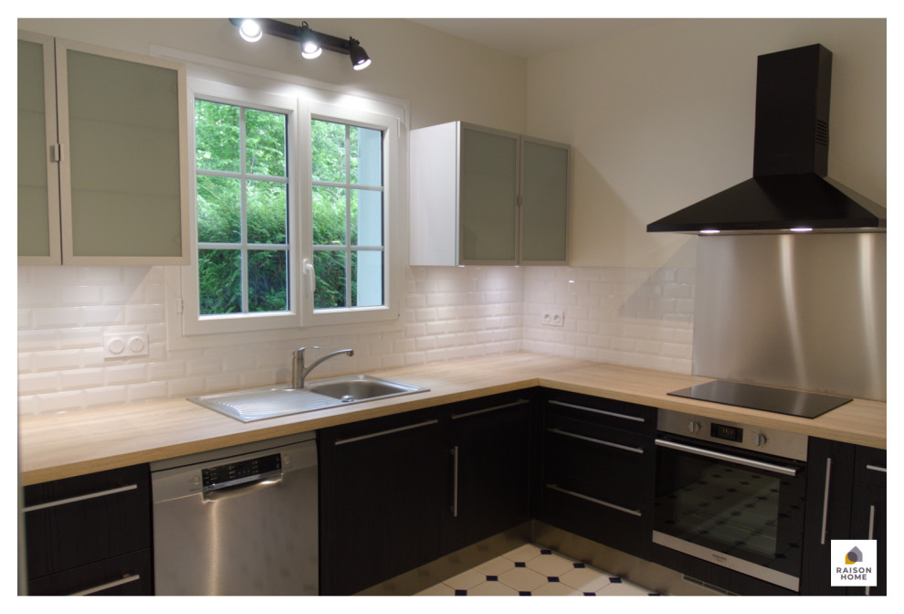 Mid-sized midcentury l-shaped open plan kitchen in Paris with an undermount sink, flat-panel cabinets, stainless steel cabinets, wood benchtops, white splashback, subway tile splashback, stainless steel appliances, cement tiles, no island, white floor, brown benchtop and wallpaper.