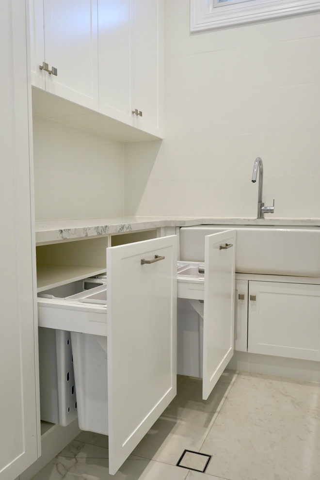 Design ideas for a large modern u-shaped dedicated laundry room in Sydney with a farmhouse sink, shaker cabinets, white cabinets, quartz benchtops, white splashback, porcelain splashback, white walls, marble floors, a side-by-side washer and dryer, white floor and white benchtop.