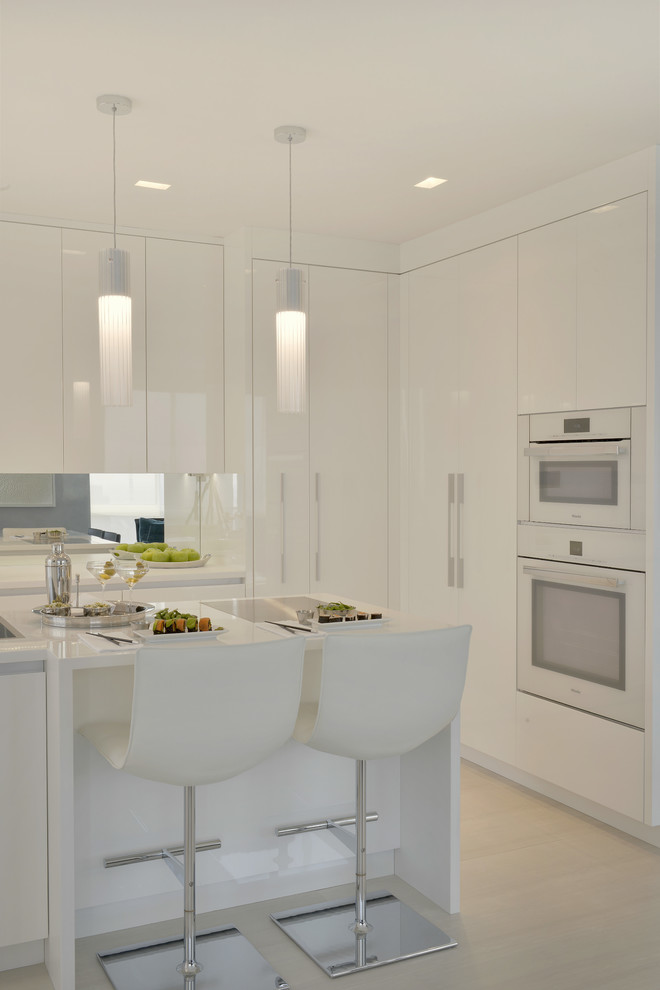 Inspiration for a small contemporary l-shaped separate kitchen in New York with an integrated sink, flat-panel cabinets, white cabinets, solid surface benchtops, mirror splashback, white appliances, porcelain floors, with island and beige floor.