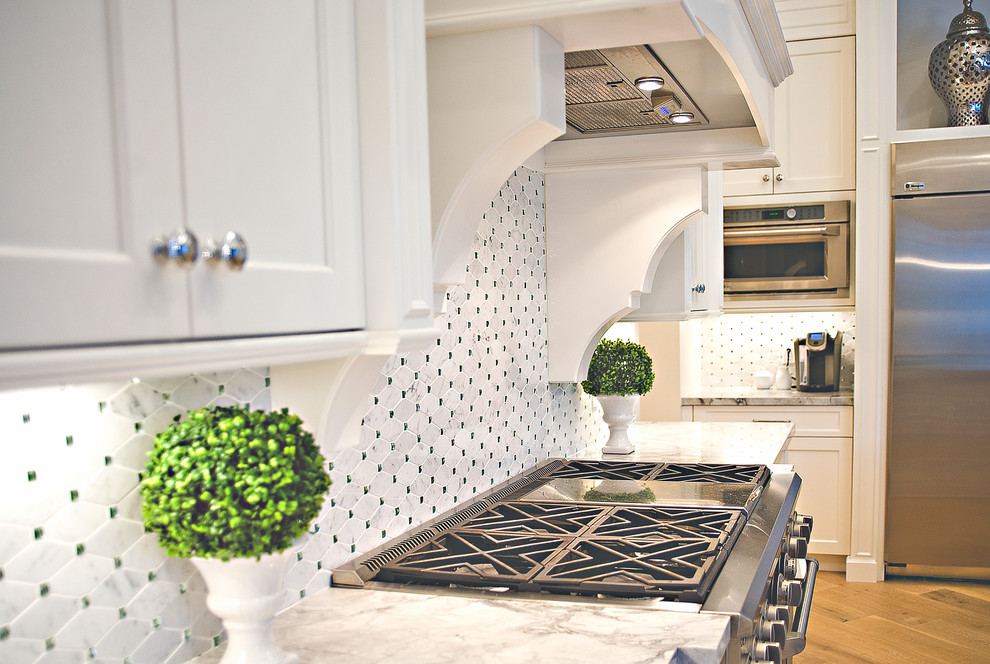 Inspiration for a large mediterranean l-shaped open plan kitchen in Miami with a double-bowl sink, recessed-panel cabinets, white cabinets, onyx benchtops, white splashback, glass tile splashback, stainless steel appliances, medium hardwood floors and with island.