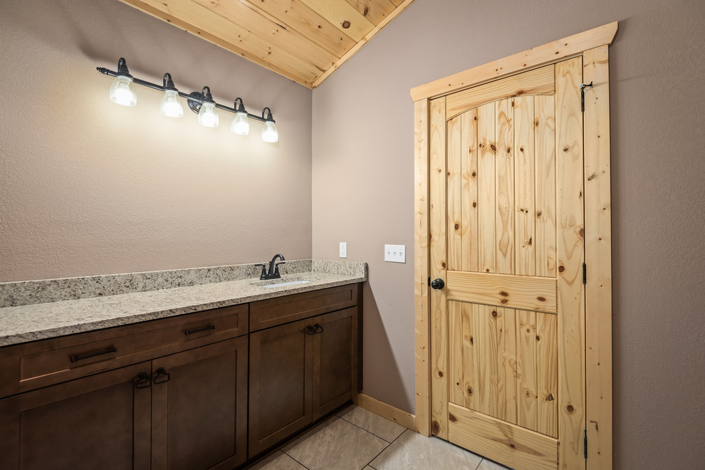 Example of a mid-sized mountain style master ceramic tile and white floor doorless shower design with recessed-panel cabinets, brown cabinets, a two-piece toilet, brown walls, an undermount sink, granite countertops and multicolored countertops