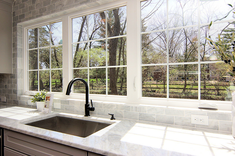 Kitchen - large transitional medium tone wood floor kitchen idea in Cincinnati with a single-bowl sink, shaker cabinets, gray cabinets, marble countertops, white backsplash, stone tile backsplash, stainless steel appliances, beige walls and an island