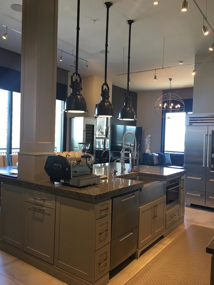 Large industrial l-shaped open plan kitchen in Atlanta with a farmhouse sink, shaker cabinets, grey cabinets, stainless steel appliances, with island, beige floor and recycled glass benchtops.